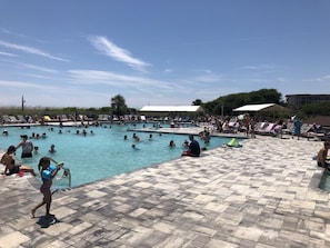 A swimming pool area with multiple pools, lounge chairs, and umbrellas.