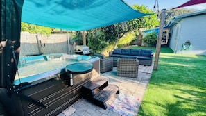 A backyard with a hot tub, outdoor seating, and a patio area.