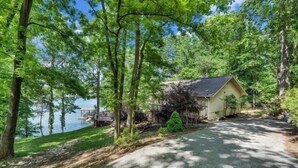 Une cabane avec un quai qui s’avance sur un lac, entourée d’arbres.