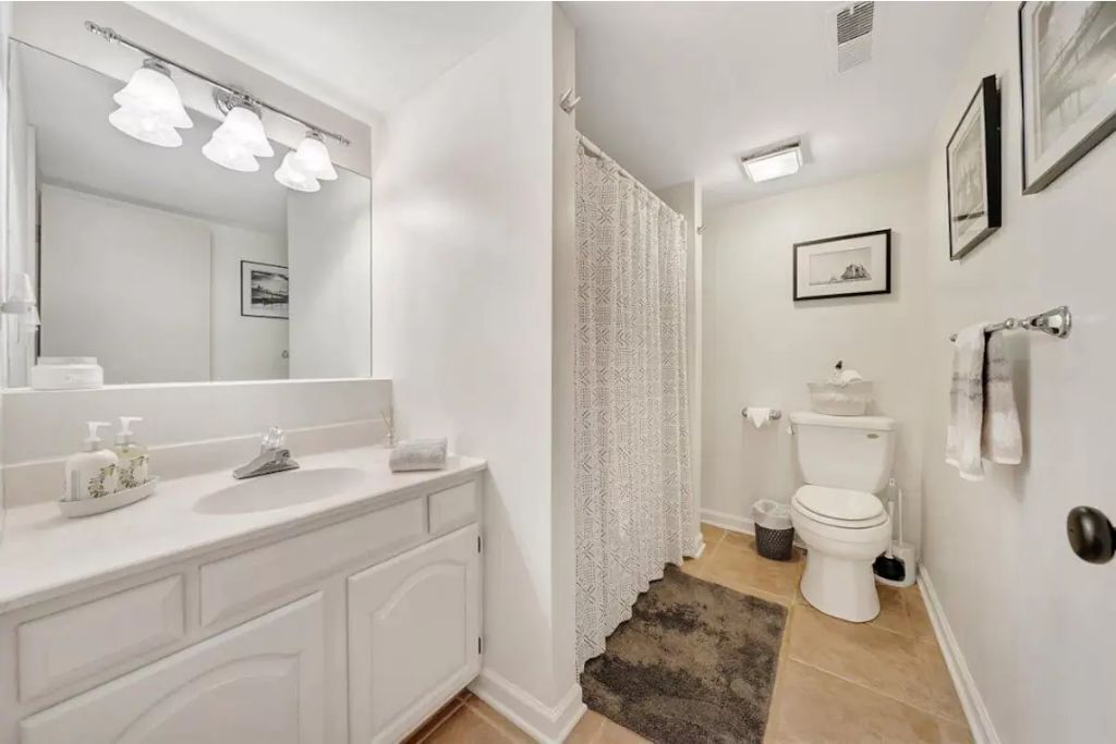 Une salle de bain avec un meuble-lavabo blanc, un grand miroir et des toilettes.