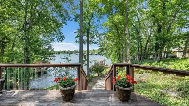 Une terrasse en bois avec une rambarde, donnant sur un lac.