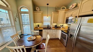 A kitchen with white cabinets, a stainless steel refrigerator, a dining table with chairs, and a window with blinds. - Beautiful Ocean Lakes site O26!  Limo cart included! Small pet friendly! (Myrtle Beach)