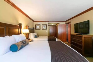 A hotel room with two beds, a television, a desk, and a dresser.