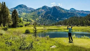 A person fishing by a lake with mountains in the background.