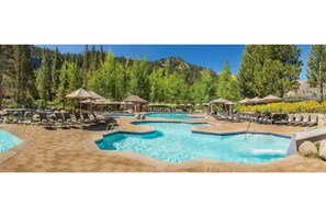 A pool area with multiple pools, lounge chairs, and umbrellas.
