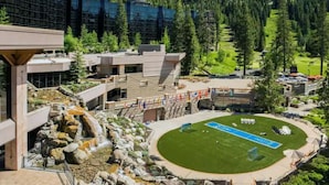 A modern hotel with a pool, surrounded by a mountainous forest.