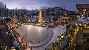 A snow-covered ice rink surrounded by buildings with festive decorations.
