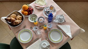 Ett frukostbord dukat med croissanter, frukt, yoghurt och en vattenflaska.