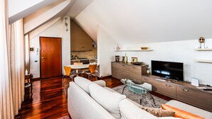 Una sala moderna con un sofá, televisor y zona de comedor.