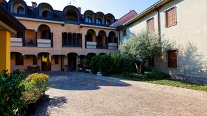 Un patio con un camino de ladrillo, varios arcos y un edificio con tejado de azulejos.