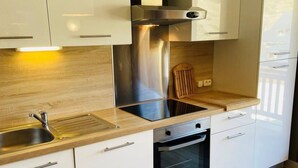 A modern kitchen with white cabinets, stainless steel appliances, and a wooden countertop.