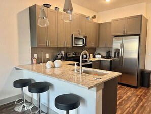 Fully equipped kitchen with a central island, stainless steel sink, and modern appliances.