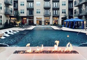 Relax by the pool with lounge chairs and umbrellas, surrounded by a modern building with balconies.