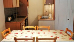 A compact kitchen with wooden cabinets, a sink, and a dining area with a table and chairs. - 100m from ski slopes, 3rd floor, balcony, tv, ski locker, 42m², Les 2 Alpes (Les Deux Alpes)