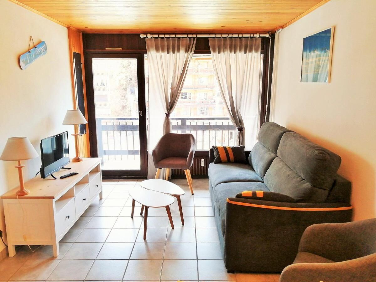 En stue med sofa, lænestol, fjernsyn, lampe og et lille bord.