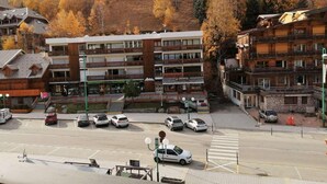A multi-story hotel with balconies, a parking lot, and a mountainous backdrop. - 100m from ski slopes, 3rd floor, balcony, tv, ski locker, 42m², Les 2 Alpes (Les Deux Alpes)