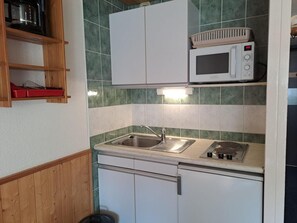 A compact kitchen with a sink, microwave, and stove.