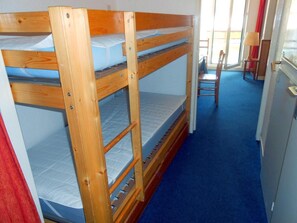 Ein Mehrbettzimmer mit blauem Teppich und einem Sessel in der Ecke.