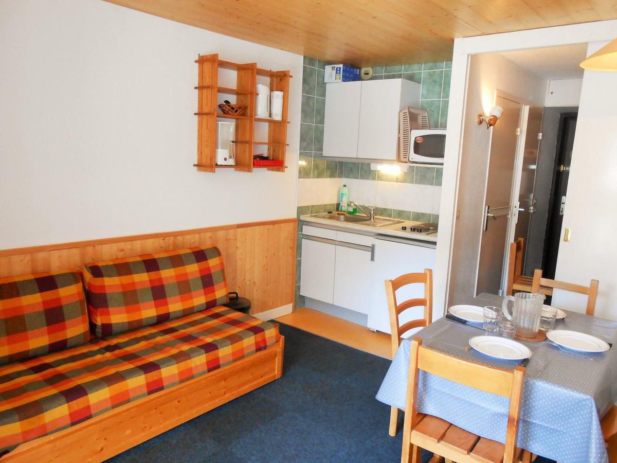 Ein gemütlicher Wohnraum mit Holzsofa, Esstisch mit Stühlen, einer Küchenzeile und einem kleinen Badezimmer.