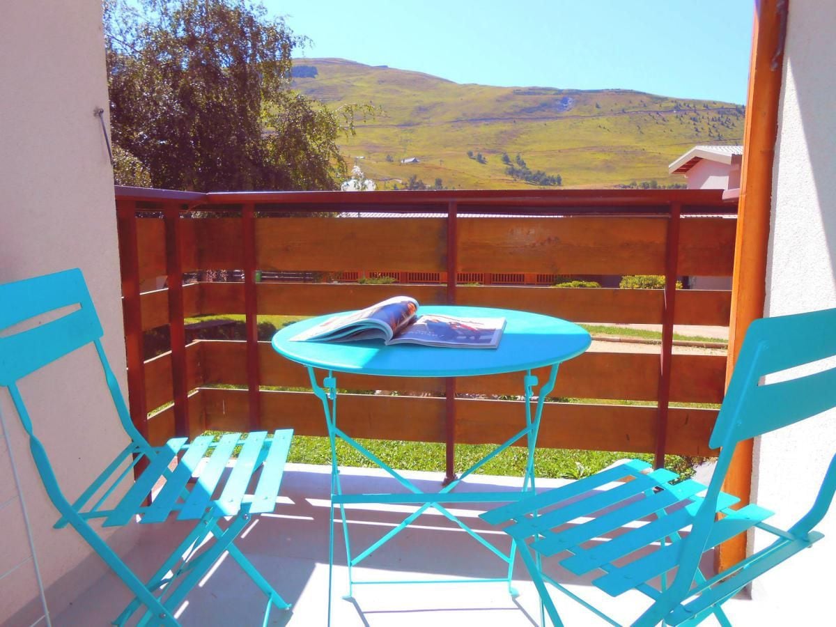 Un balcone con un tavolo e due sedie, affacciato su un paesaggio collinare.
