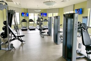 Un gimnasio con cintas de correr, máquinas de pesas y equipo cardiovascular.