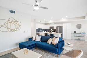 A modern living room with a blue sectional sofa, a coffee table, and a kitchen in the background. - 3171-206 Resort Lake View Disney Universal Orlando (Kissimmee)