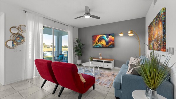 Ein modernes Wohnzimmer mit einem roten Sessel, einem blauen Sofa, einem weißen Couchtisch und einem Gemälde an der Wand.