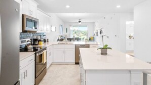 Une cuisine moderne avec des meubles blancs, des appareils en acier inoxydable et un îlot central.