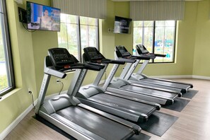 A row of treadmills in a gym with large windows and a TV on the wall. - 3150-106 Resort Pool View Disney Universal Orlando (Kissimmee)
