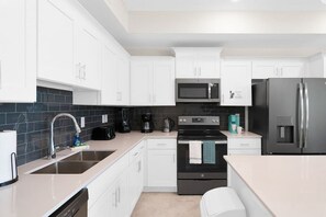 A modern kitchen with white cabinets, a black stove, a stainless steel refrigerator, and a microwave. - 3150-106 Resort Pool View Disney Universal Orlando (Kissimmee)