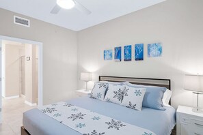 Une chambre à coucher avec un lit, des tables de chevet et un ventilateur de plafond.