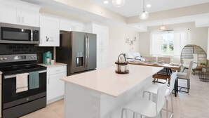 A modern kitchen with white cabinets, a black stove, stainless steel appliances, and a central island with bar stools. - 3150-106 Resort Pool View Disney Universal Orlando (Kissimmee)