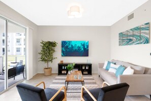 Un salon moderne avec un canapé, une table basse et un grand tableau abstrait.