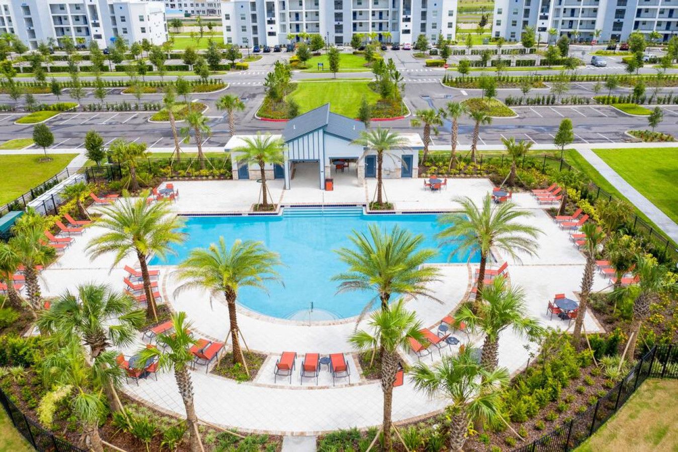 A resort with a central swimming pool, palm trees, and a covered area with seating.