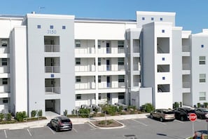 A multi-story residential building with balconies, numbered 3150, parking in front. - 3150-106 Resort Pool View Disney Universal Orlando (Kissimmee)