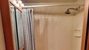 Une salle de bain équipée d’un lavabo, d’un miroir, d’une douche et de toilettes.