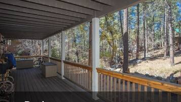 A covered deck with a view of a forested area.