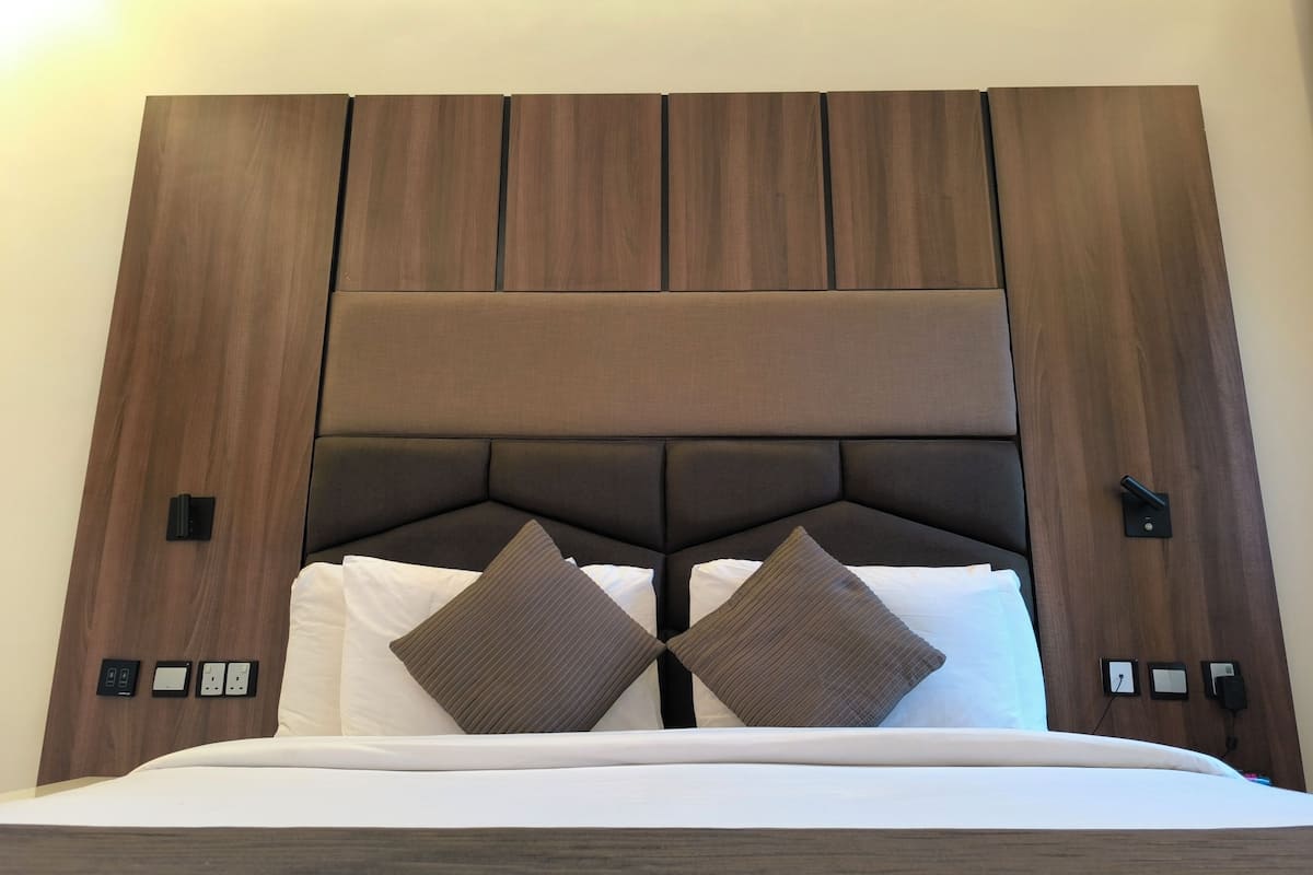 A bed with a wooden headboard, two pillows, and a white bedspread.