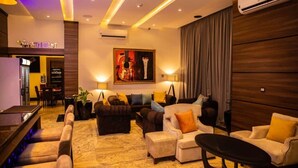 A modern hotel lobby with a seating area, a restaurant sign, and an air conditioning unit. - OMEDEL LUXURY (Enugu)