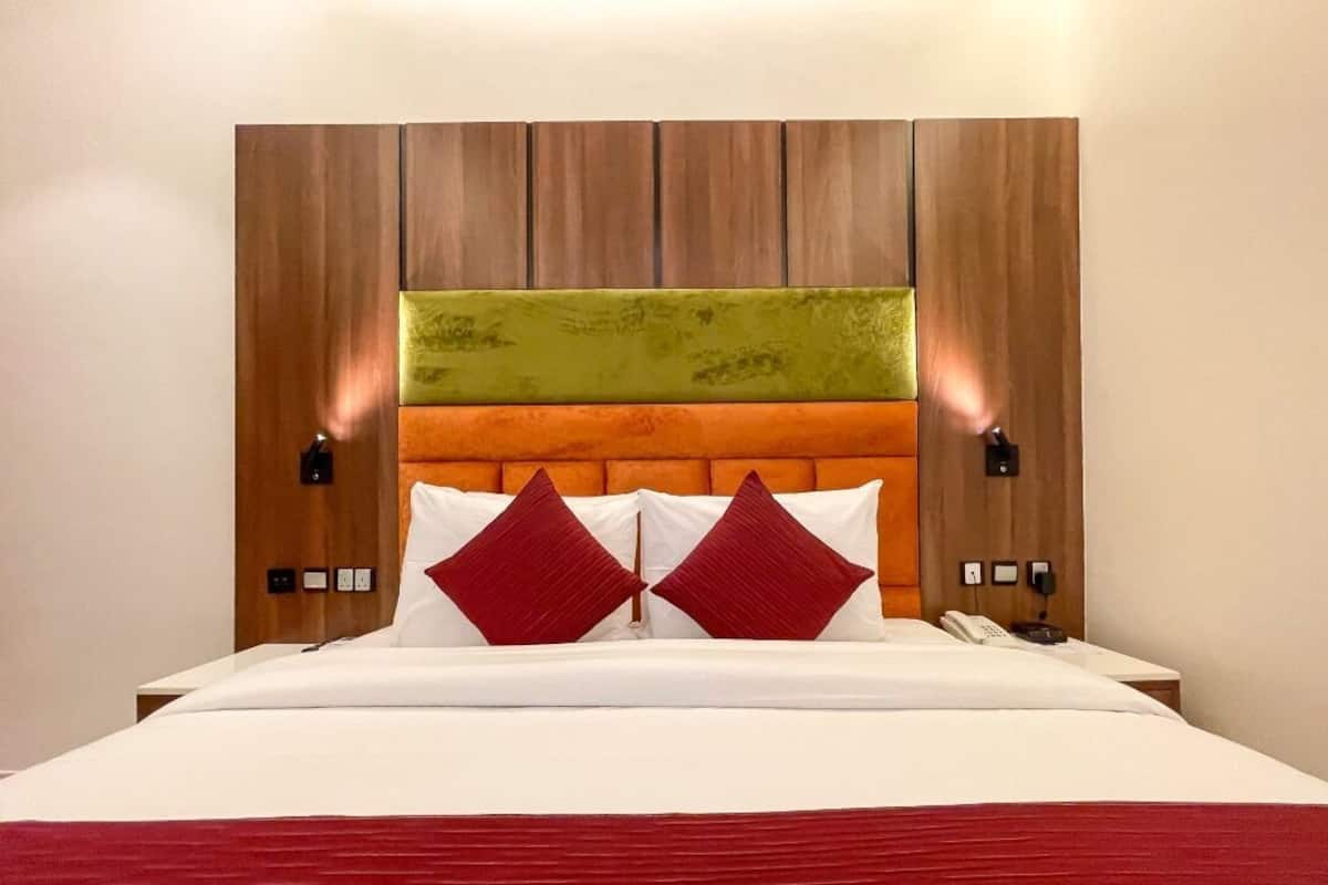 A hotel room with a large bed, a wooden headboard, and two bedside lamps.