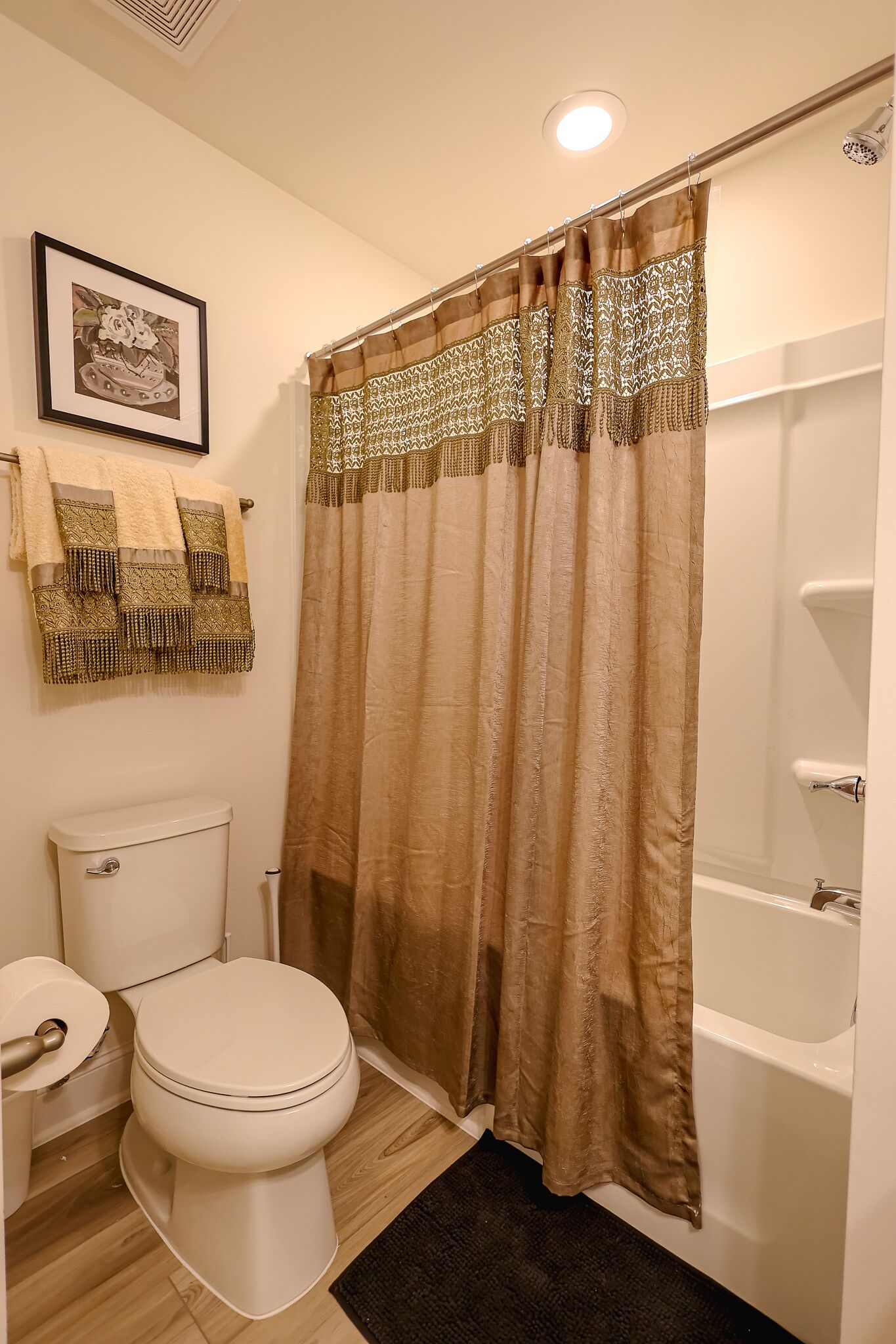 Ein Badezimmer mit Toilette, Duschvorhang und Handtuchhalter mit Handtuch.
