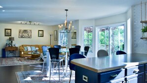 A spacious living room with a large dining area, a kitchen with a central island, and a view of the outdoors through large windows. - Bright & Spacious 3 Bedroom Home in Coveted Loveland Neighborhood! (Loveland)
