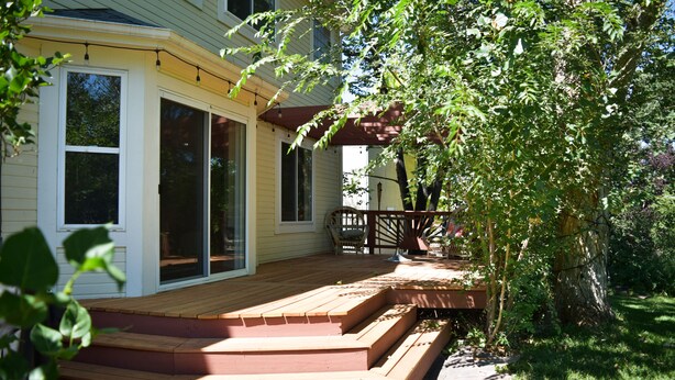 A house with a wooden deck, a covered porch, and a large sliding glass door. - Bright & Spacious 3 Bedroom Home in Coveted Loveland Neighborhood! (Loveland)