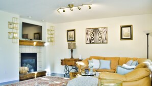 A living room with a fireplace, a sofa, a coffee table, and a patterned rug. - Bright & Spacious 3 Bedroom Home in Coveted Loveland Neighborhood! (Loveland)
