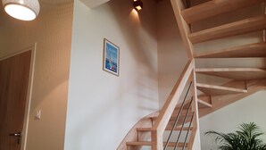 Eine Holztreppe mit Handlauf, einer Wandleuchte und einem gerahmten Bild.