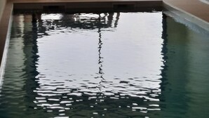 Ein Hallenbad mit Blick auf einen bewaldeten Hügel und ein Gewässer.