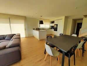 A modern living space with a dining area, kitchen, and a sofa.