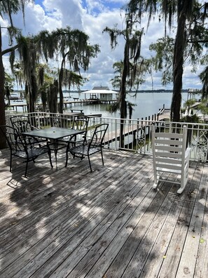 A wooden deck with a table and chairs, overlooking a calm lake with a dock and a small house. - GilligansIslandResort.com White Lake Mansion w/Pvt Pier & Boat Dock Sleeps 18 (Elizabethtown)