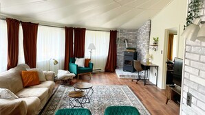 Una sala de estar acogedora con un sofá, sillones, una mesa de centro, chimenea y comedor.