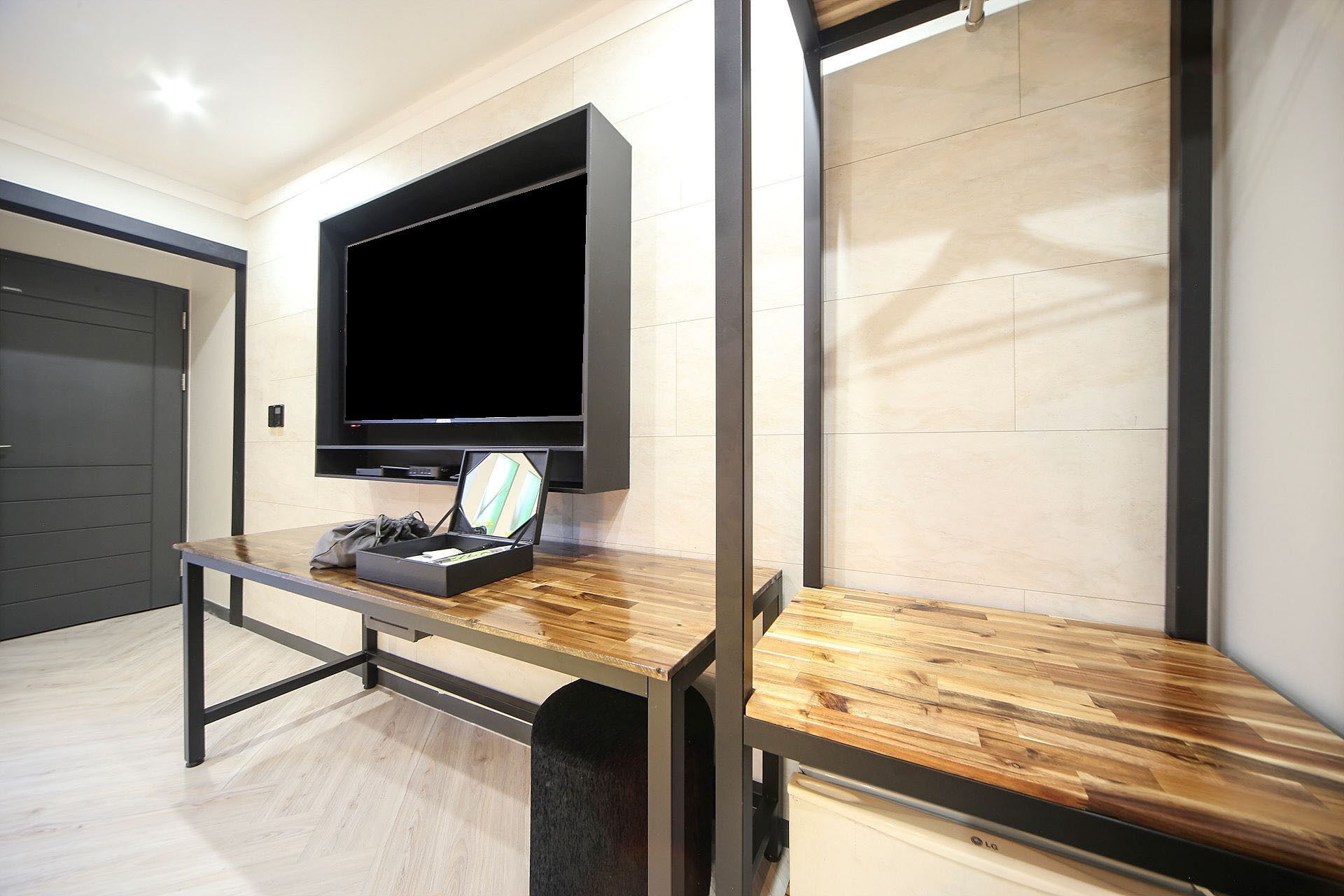 A modern living room with a flat-screen TV mounted on the wall, a wooden coffee table, and a grey bag on the table.